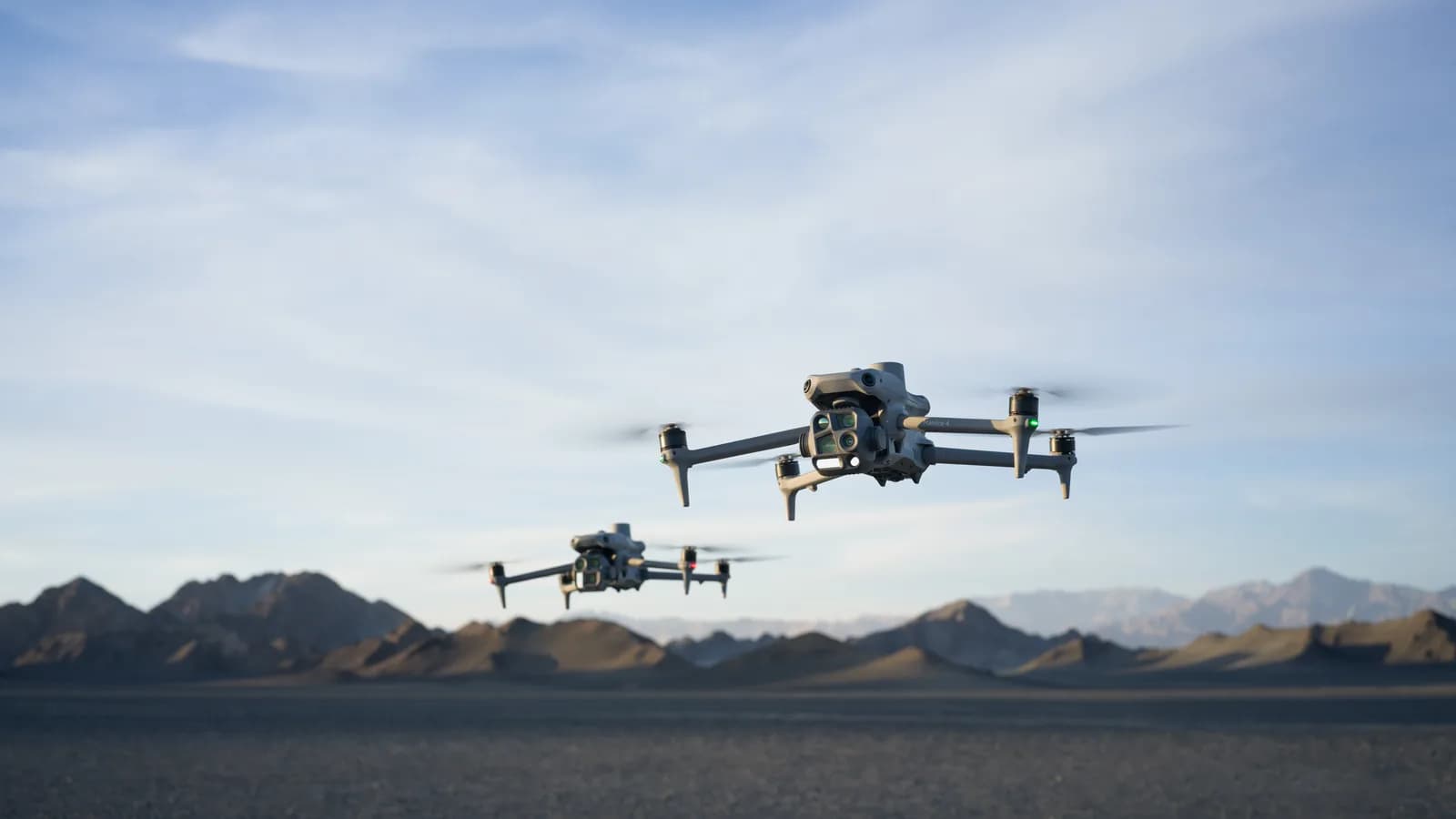 Deux drones DJI de la gamme Matrice 4 en vol au-dessus d'une plaine désertique