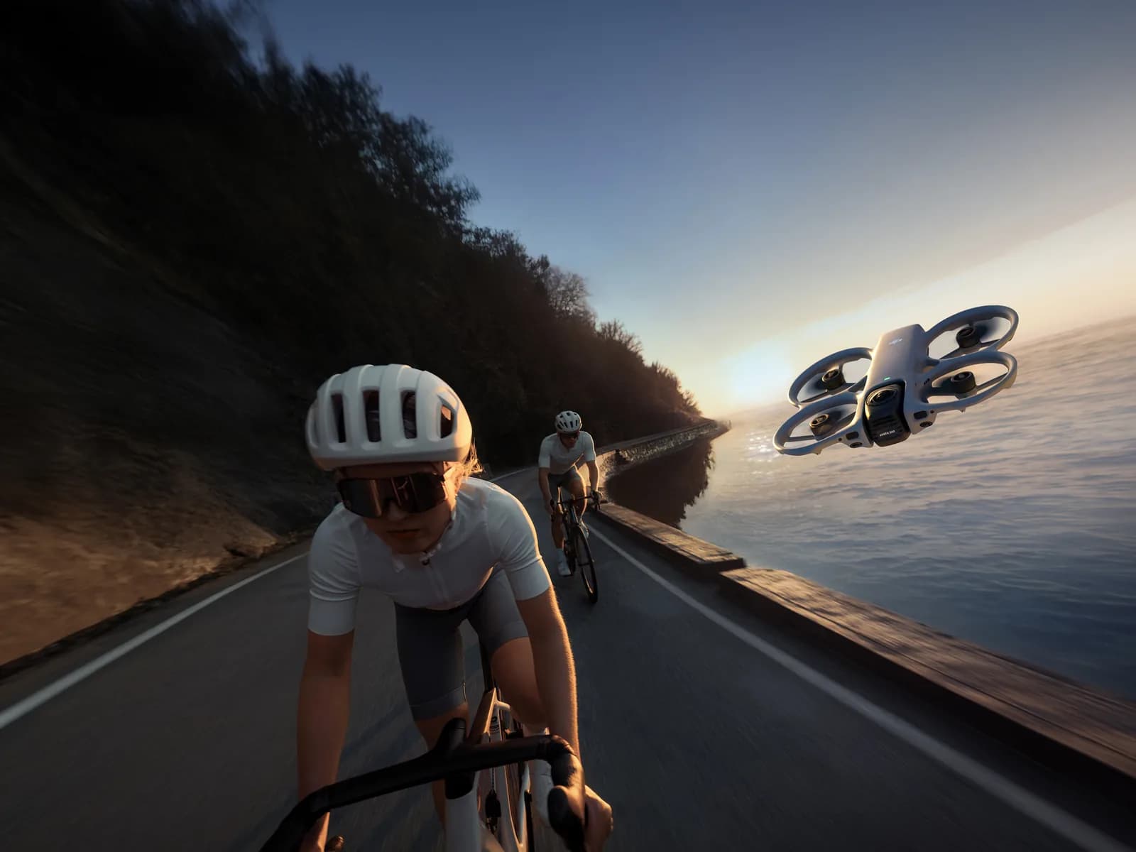 DJI Avata 360 filmant deux cyclistes sur une route en bord de mer au coucher du soleil