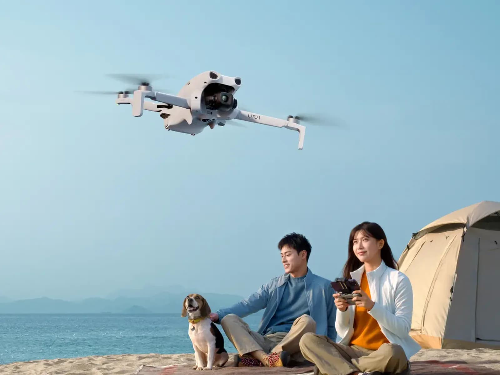 DJI Lito 1 en vol au-dessus d'une plage, famille installée près d'une tente