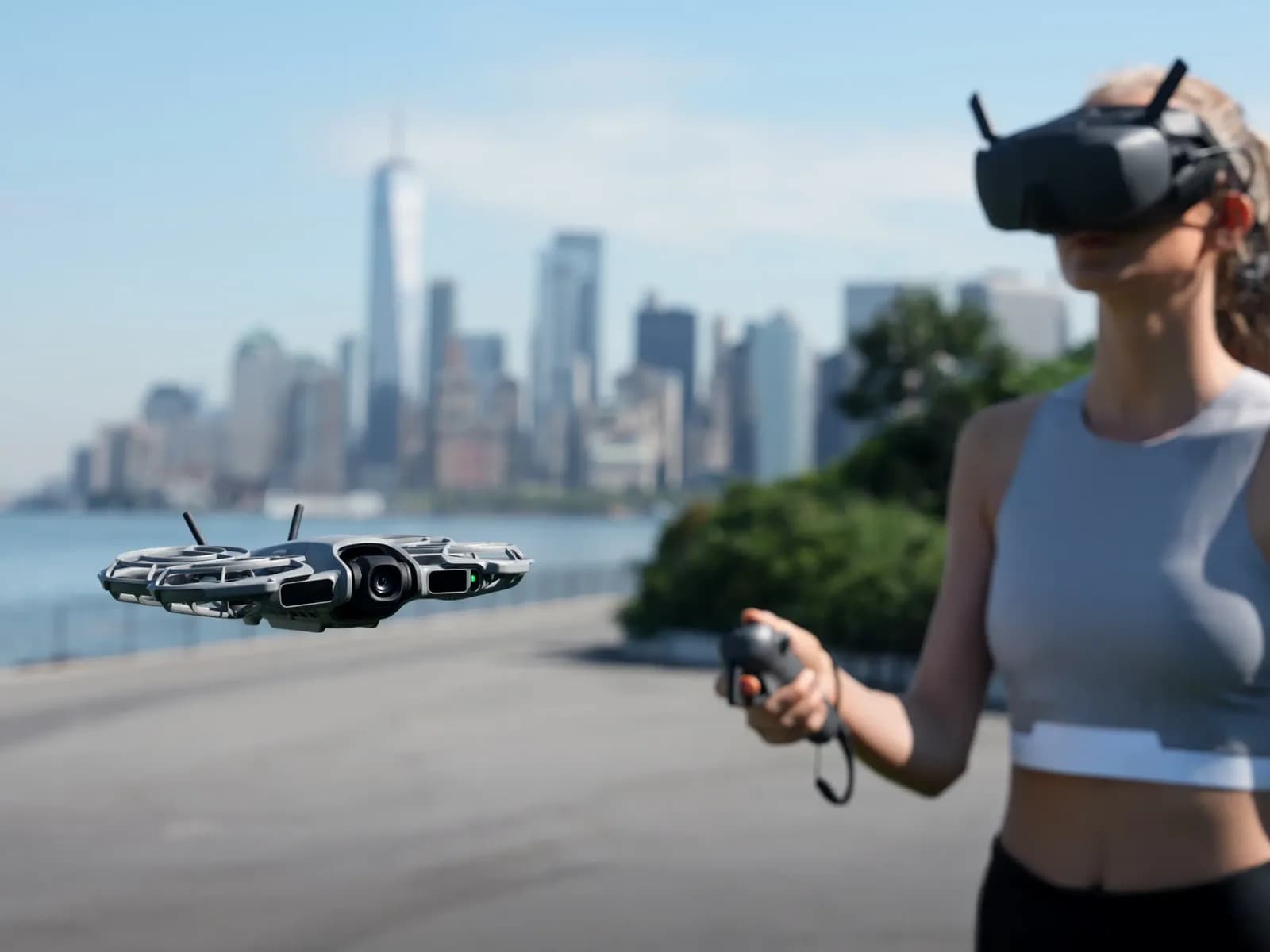 Pilote équipé de lunettes FPV et d'une manette de mouvement, DJI Neo 2 en vol près d'une ville